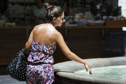 Una mujer se refresca en una fuente en Valencia.