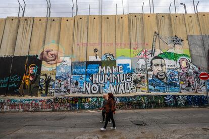 Dos mujeres pasan delante del muro en Belén, Cisjordania. La barrera, de más de 700 kilómetros, deja viviendas palestinas rodeadas por asentamientos y dificulta a sus habitantes acceder a sus tierras.
