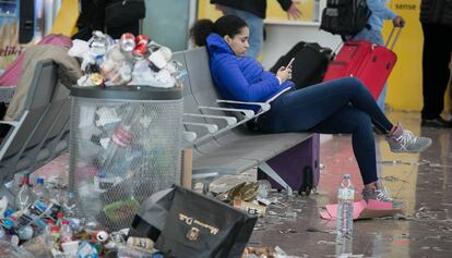 Una mujer espera en la T1 entre montones de basuras.