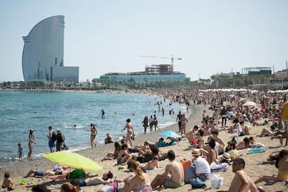 Turistes a la platja amb l&#039;Hotel Vela al fons.