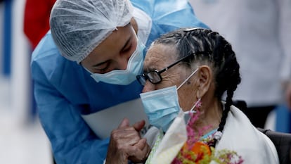 Joaquina Garzón, de 92 años, lleva un ramo de flores mientras usa una mascarilla, durante su alta del Hospital Suesca donde se recuperó de la covid-19 en Suesca, Colombia, 23 de abril de 2020.