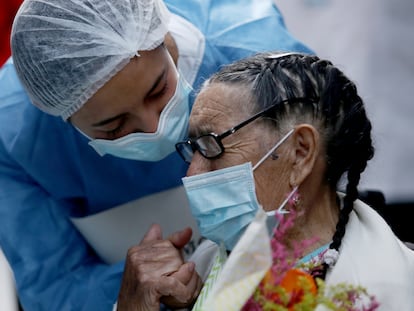 Joaquina Garzón, de 92 años, lleva un ramo de flores mientras usa una mascarilla, durante su alta del Hospital Suesca donde se recuperó de la covid-19 en Suesca, Colombia, 23 de abril de 2020.