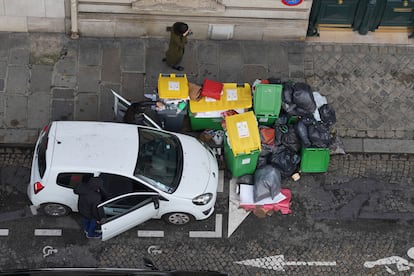 Parisinos entrando en un coche con la calle llena de bolsas de basura, este martes. Miles de toneladas de basura se acumulan en las calles de la capital francesa después de una semana de huelga de los servicios de recogida de basuras en contra de la reforma de las pensiones del gobierno francés.