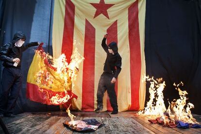 Un encapuchado quema un retrato del Rey y una bandera epañola y otras francesa tras la manifestación independentista en Barcelona.