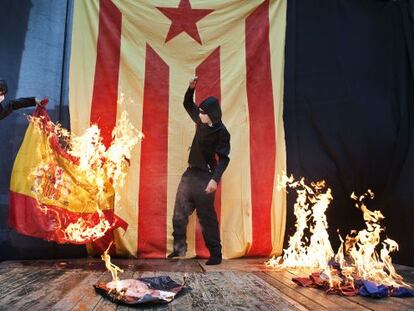 Un encapuchado quema un retrato del Rey y una bandera española, en octubre de 2019 en Barcelona.