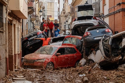  Vecinos de Paiporta intentan pasar entre una montonera de vehículos arrastrados por la corriente, este viernes. 