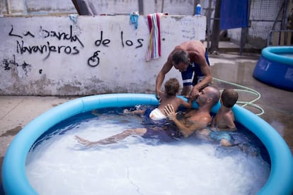 Varios vecinos se refrescan en una piscina hinchable en el asentamiento chabolista de El Vacie, en Sevilla.