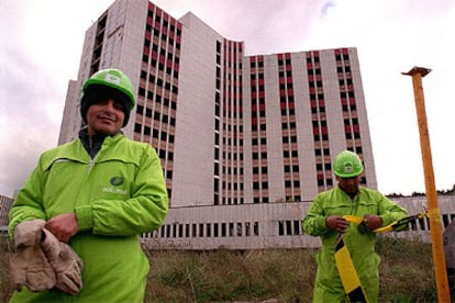 Dos operarios frente al hospital de Leioa, que espera para ser domolido.