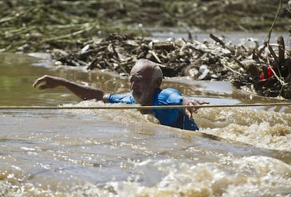 Un hombre trata atravesar de atravesar una calle inundada en Acapulco.