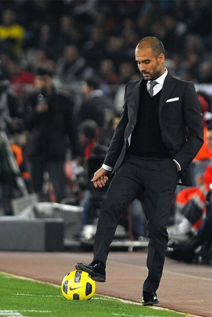 Guardiola controla el balón en la banda durante el partido.