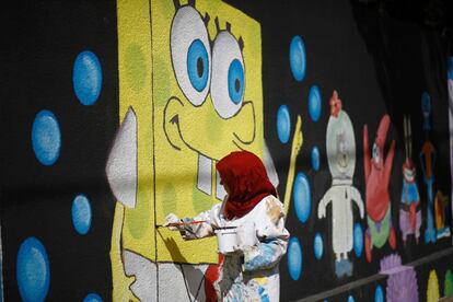 Un artista palestino realiza pinturas murales en las paredes de una escuela dirigida por el organismo de obras públicas y socorro de las Naciones Unidas para los refugiados de Palestina. 