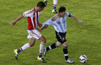 El mediocentro paraguayo V&iacute;ctor C&aacute;ceres intenta frenar a Messi agarr&aacute;ndole la camiseta durante el partido del s&aacute;bado.