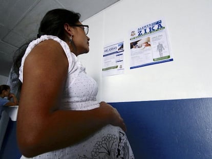 Mujer embarazada lee un anuncio sobre el virus del zika.