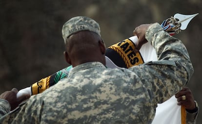 Un soldado retira la bandera de las Fuerzas Armadas durante la ceremonia.