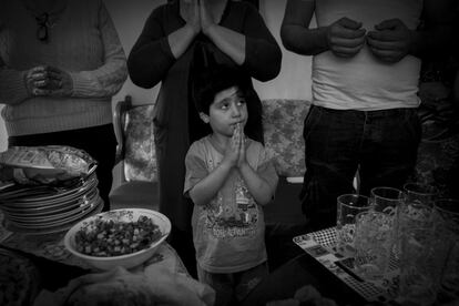 Un niño acompaña el rezo antes del almuerzo de cumpleaños de Andrya Banoosha, cabeza de familia que huyó de Irak con su familia.