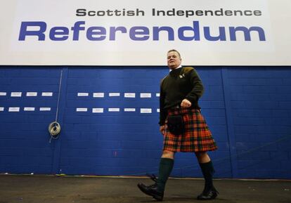 Un hombre con el tradicional traje escocés camina durante el conteo de votos del referéndum en el Centro Royal Highland.