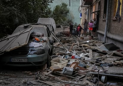 Residentes de la capital de Ucrania observan la destrucción del ataque ruso sobre un edificio en Kiev, este jueves.