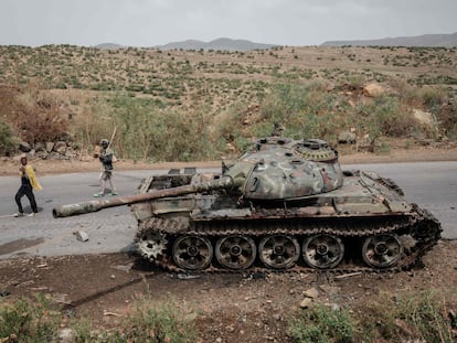 Dos agricultores pasan junto a un tanque abandonado en la carretera en Dansa, al suroeste de Mekele, en la región etíope de Tigray, el 20 de junio de 2021.