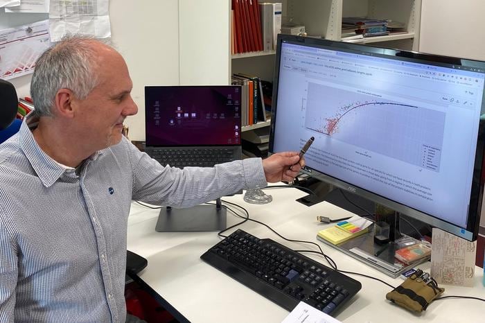 El biólogo computacional Enrique Muro señala una gráfica sobre la transición de fase en la Universidad de Maguncia, Alemania.