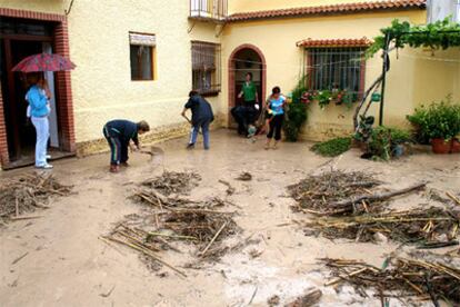 Varios vecinos intentan limpiar el barro dejado por la lluvia que ha caído esta madrugada en Cuevas Bajas (Málaga).