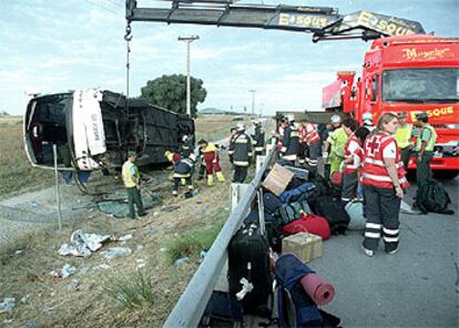 Una grúa levanta el autocar accidentado, tras evacuar a todos los pasajeros y recuperar sus equipajes.