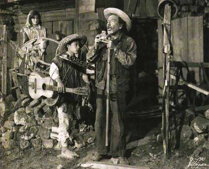 Ojitos (Mario Ramírez) asiste a una actuación del ciego Don Carmelo (Miguel Icián), en presencia de Meche (Alma Delia Fuentes), en un fotograma de <i>Los olvidados</i>.