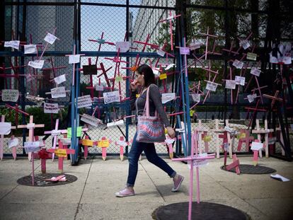 Una mujer pasa delante de cruces por las víctimas de feminicidios.