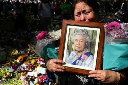 Una mujer llora con una imagen de la monarca antes de depositar flores en un parque de Londres, este domingo.
