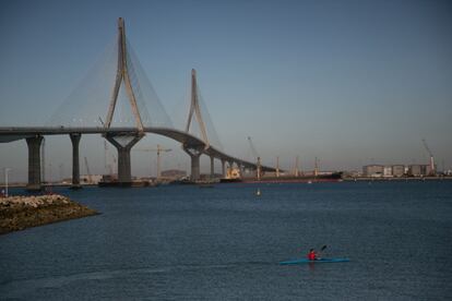 Un aficionado al remo pasa delante del nuevo puente gaditano con su kayak.