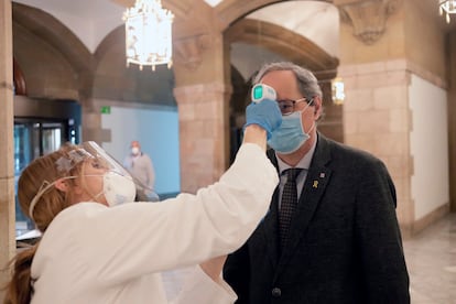 Un miembro de los servicios médicos toma la temperatura al presidente de la Generalitat, Quim Torra, a su llegada al Parlament donde se celebra el debate final de los presupuestos de la Generalitat para 2020.