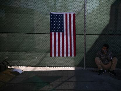 Un migrante reposa junto a una bandera de Estados Unidos, en una calle de El Paso, el pasado 21 de diciembre.