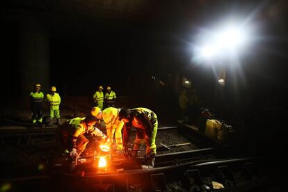 Varios técnicos trabajan en la unión de una via que previamente han seccionado para repararla en un túnel cerca de la estación de Atocha.