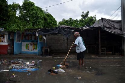 Una mujer intenta limpiar una calle de la basura que el huracán Matthew ha llevado, en Puerto Príncipe.