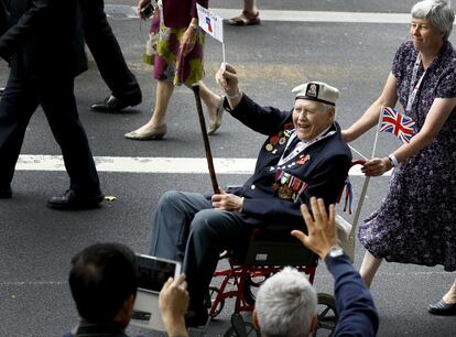 Un veterano de las ondas de una bandera durante el desfile para conmemorar VJ día, a medida que pasa a lo largo de Whitehall en el centro de Londres.