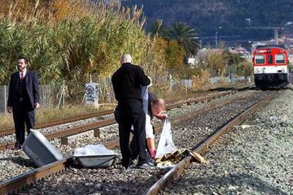 Dos funcionarios retiran los cadáveres de los dos menores arrollados por un tren de cercanías en Murcia.
