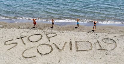 Los mienbros de una familia escribe la frase "Stop Covid-19" en la arena de una playa de Nápoles, Italia.