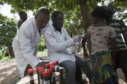 Recolección comunitaria de muestras de orina para evaluar la esquistosomiasis urinaria y la evaluación del estado nutricional. Uno de los investigadores está tomando la circunferencia del brazo medio-superior de una mujer, mientras otro toma registro.

