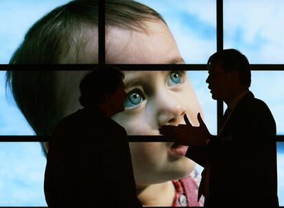 Dos hombres conversan frente a un mural de pantallas de plasma. Pese a lo que pudiera parecer, en el mundo siguen vendiéndose más las televisiones tradicionales.