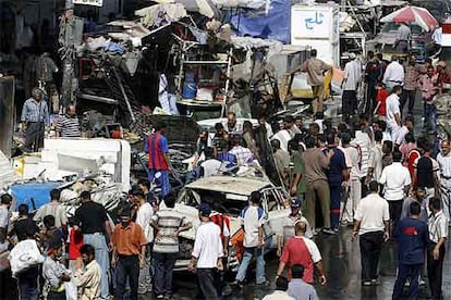 Grupos de iraquíes observan los daños causados ayer en el lugar de la explosión en el mercado de Shorya, en Bagdad.