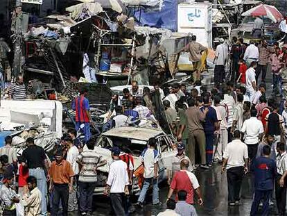 Grupos de iraquíes observan los daños causados ayer en el lugar de la explosión en el mercado de Shorya, en Bagdad.