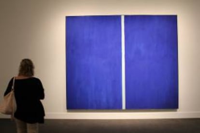 Fotografía en la que una mujer observa la obra "Onement VI", de Barnett Newman, que se convirtió en la estrella de la subasta de arte contemporáneo celebrada en Nueva York por la casa Sotheby's, en la que alcanzó un precio de 43,8 millones de dólares, tras incluir impuestos y comisiones.