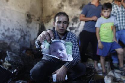 Un familiar del nen palestí mort mostra la seva fotografia a l'interior de la casa atacada amb còctels Molotov.