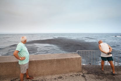 Dos vecinos de Candelaria observaban la gran mancha de ceniza en el mar a consecuencia del fuego forestal que afecta a los montes de los municipios Arafo y Candelaria, el miércoles.