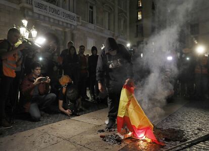 Un encapuchado quema una bandera española en la plaza de Sant Jaume de Barcelona.