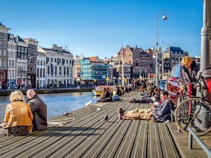 Decenas de turistas descansas a orillas de uno de los canales de Ámsterdam.