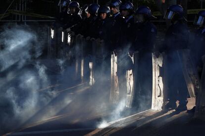 El humo de un cohete envuelve a la policía antidisturbios durante ante el Parlamento de Nicosia en protesta por la ley de privatizaciones (Chipre).