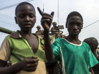 Dos menores posan mientras unos militares franceses realizan maniobras con un tanque en el distrito PK12 de Bangui (Repúyblica Centroafricana)  el 23 de febrero de 2014.