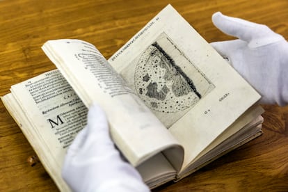 La directora técnica de la biblioteca, con guantes, muestra páginas del atlas lunar.