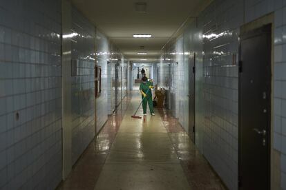 El equipo de limpieza, con bata o uniforme verde y guantes amarillos, es el único que sale al pasillo en el hospital de Svitlodarsk. 