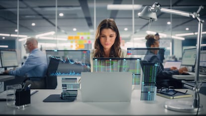 Young Happy Businesswoman Using Laptop Computer in Modern Office with Colleagues. Stylish Beautiful Financial Advisor Working. VFX Hologram Edit Visualizing Stock Exchange Interface, Opened Charts.